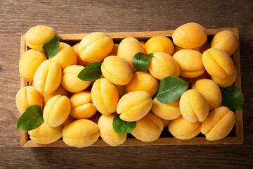 fresh ripe apricots with leaves in a box on a wooden table