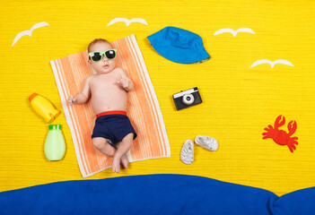 Cute child in swimming trunks is lying on a towel. Summer vacation