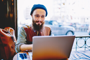 Positive male copywriter reading information on websites for writing content article using free...
