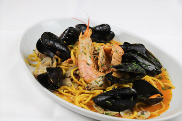 Spaghetti with seafood.Spicy spaghetti with mussels, clams, calamari, shrimp, crab, in tomato sauce close-up on a plate.Famous mediterranean Italian seafood dish -spaghetti allo scoglio