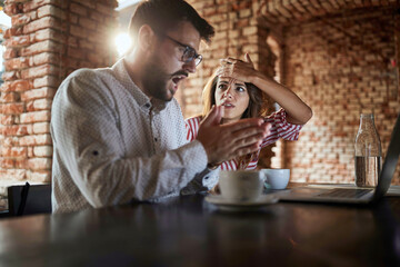 young caucasian couple looking at laptop in front of them, receiving bad news, made mistake