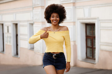 dark-skinned African American shows off a sign with her hand and smiles. Summer