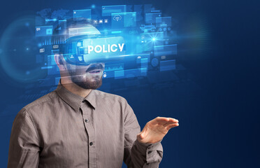 Businessman looking through Virtual Reality glasses with POLICY inscription, innovative security concept