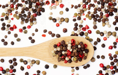 Wooden spoon with pepper on a white background top view