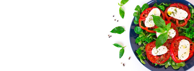 Italian caprese salad with ripe tomatoes and mozzarella cheese with fresh basil leaves and corn salad. Delicious food. White background with space for text. Banner. Healthy and tasty dinner. Top view