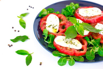 Caprese Salad made of mozzarella, tomatoes, lamb's lettuce and basil with pepper, olive oil. Ready to eat on white background. DIY Italian food