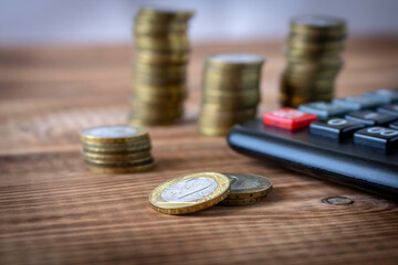 A stack of coins and a calculator on a wooden table. Concept of savings and financial accounting. Selective focus.