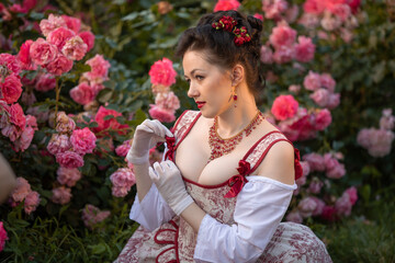 woman bride in a ancient vintage historical dress posing in the beautiful summer rose garden