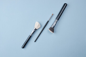 large and small brushes for drawing and make-up on a blue background. copy space for text. top view.