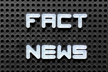 White color alphabet with word fact news on black pegboard background