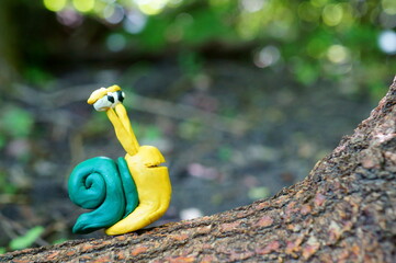 Snail made of plasticine on a colored natural background.