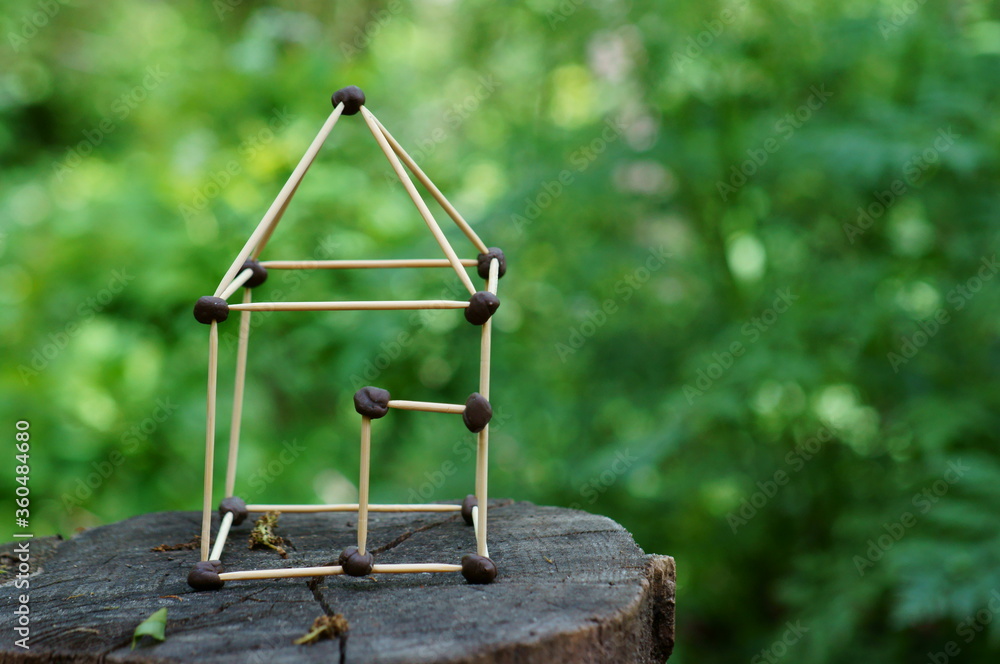 Wall mural toy house made of toothpicks on a wooden background.