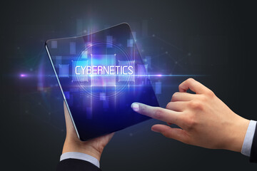 Obraz na płótnie Canvas Businessman holding a foldable smartphone with CYBERNETICS inscription, new technology concept