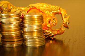 Hotei figurine with coins on a gold background.