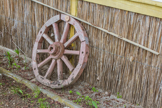 Wooden vintage wheel on a background of a reed wall