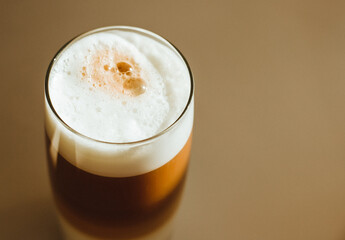 Coffee latte with white foam poured in layers in a transparent glass. High glass photographed from above.