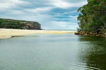 Panoramic views of Wattamolla Beach with waterfall tress turquoise blue waters and nice white sandy beach in sydney NSW Australia