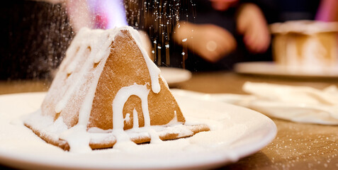 A close up of Gingerbread house under snow. a piece of cake. 