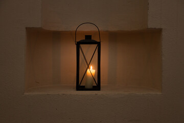 black lantern in niche of a beige wall