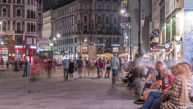 People walking in the Old city center of Vienna in Stephansplatz night timelapse. Shops and restaurants around, crowded place