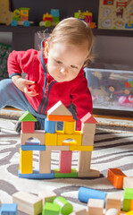 Cute child having fun playing with colorful wooden blocks, at home.