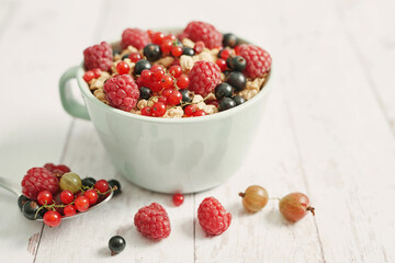 Colorful fresh berries on white background. Oatmeal with berries currants, raspberries, gooseberries. Vitamins, Diet. Copy space. Healthly food, detox. Cozy good morning! Summer Healthy breakfast