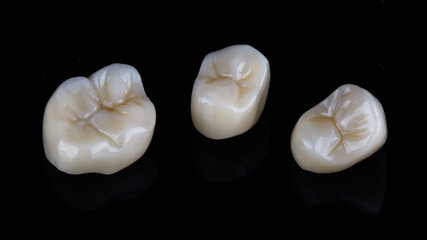three high quality dental crowns on a black background