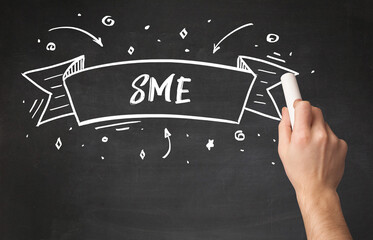 Hand drawing SME abbreviation with white chalk on blackboard