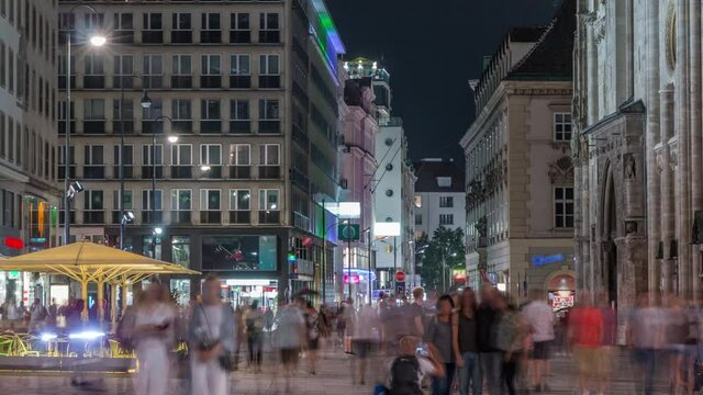 People walking in the Old city center of Vienna in Stephansplatz night timelapse. Shops and restaurants around, crowded place