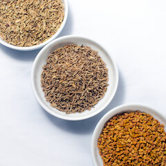 A mixture of Ceylon spices:  Cumin seeds, Caraway seeds, Mustard seeds, Fenugreek Seeds place in bowls.  Arranged in a row. 