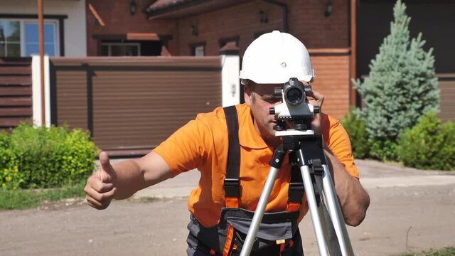 Professional Construction Surveyor Working with Leveling Instrument on Construction Site