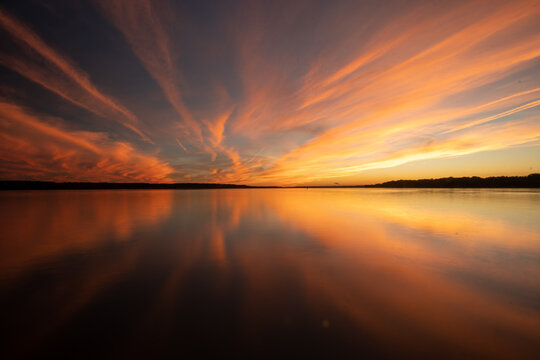 Colorful Golden and Orange Sunset Sky Over River With Reflections in the Calm Water