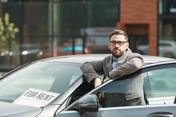 Fototapeta na wymiar Portrait of mature bearded businessman in eyeglasses looking at camera while standing near the car outdoors