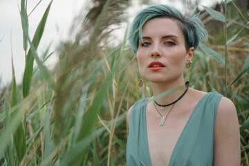 Fototapeta premium Portrait of a young beautiful girl in a blue bathing suit in the thicket of reeds