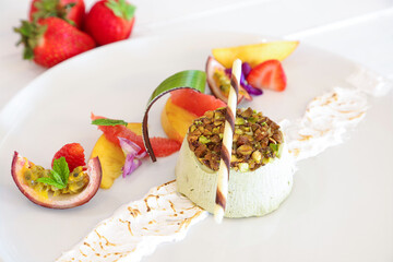 Delicious dessert with pistachio and fresh fruit on a white plate
