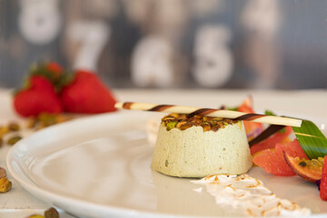 Delicious dessert with pistachio and fresh fruit on a white plate