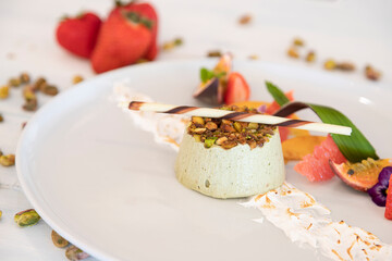 Delicious dessert with pistachio and fresh fruit on a white plate