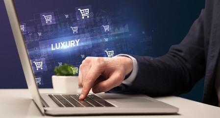 Fototapeta na wymiar Businessman working on laptop with LUXURY inscription, online shopping concept