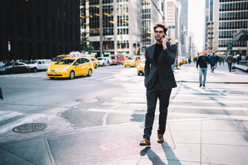 Confident proud CEO strolling on New York street and talking with business partner on smartphone discussing last financial news.Successful economist in stylish formal wear communicating on telephone