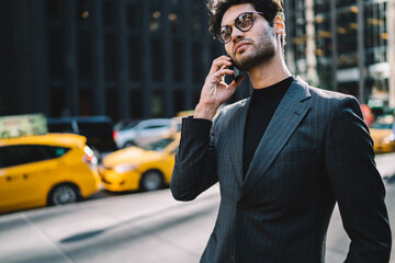 Serious proud ceo in trendy elegant suit having mobile phone consultancy with banking operator strolling on Manhattan, confident businessman talking on smartphone in roaming spending time in downtown.