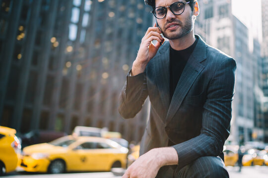 Cropped image of confident trader dressed in stylish suit talking with business partner on smartphone standing on Manhattan street.Serious economist angry with bad news during mobile conversation