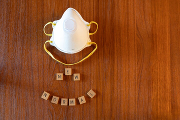 N95 mask and new normal spelled out against a wooden background