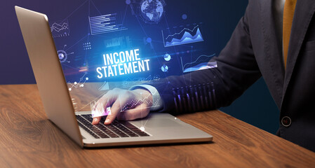 Businessman working on laptop with INCOME STATEMENT inscription, new business concept