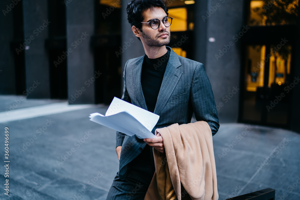 Aufkleber successful handsome entrepreneur dressed in stylish formal wear holding paper documentation with inf