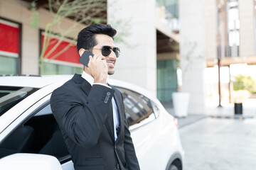 Businessman Talking On Mobile Phone By Car