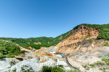 Jigokudani hell valley walking trail in Noboribetsu, Hokkaido, Japan. Selective focus at front banister of wooden footpath.