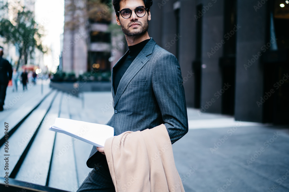 Aufkleber cropped image of confident businessman in formal apparel with paper reports in hands walking on stre