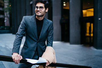 Smiling prosperous male executive manager in legant outfit smiling looking away spending time...