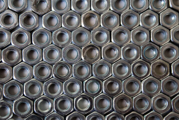 Background of orderly laid metal nuts. Honeycombs made of shiny metal nuts