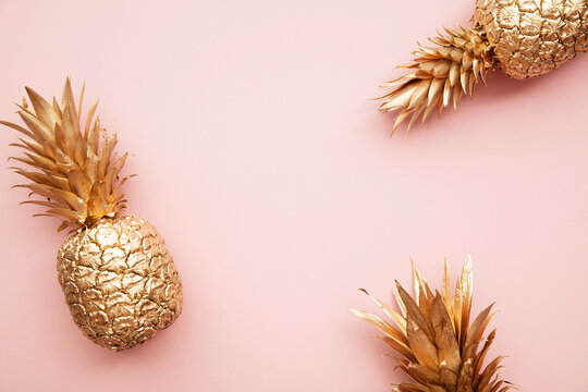 Gold tropical pineapple on a pastel pink background. Flat lay summer background